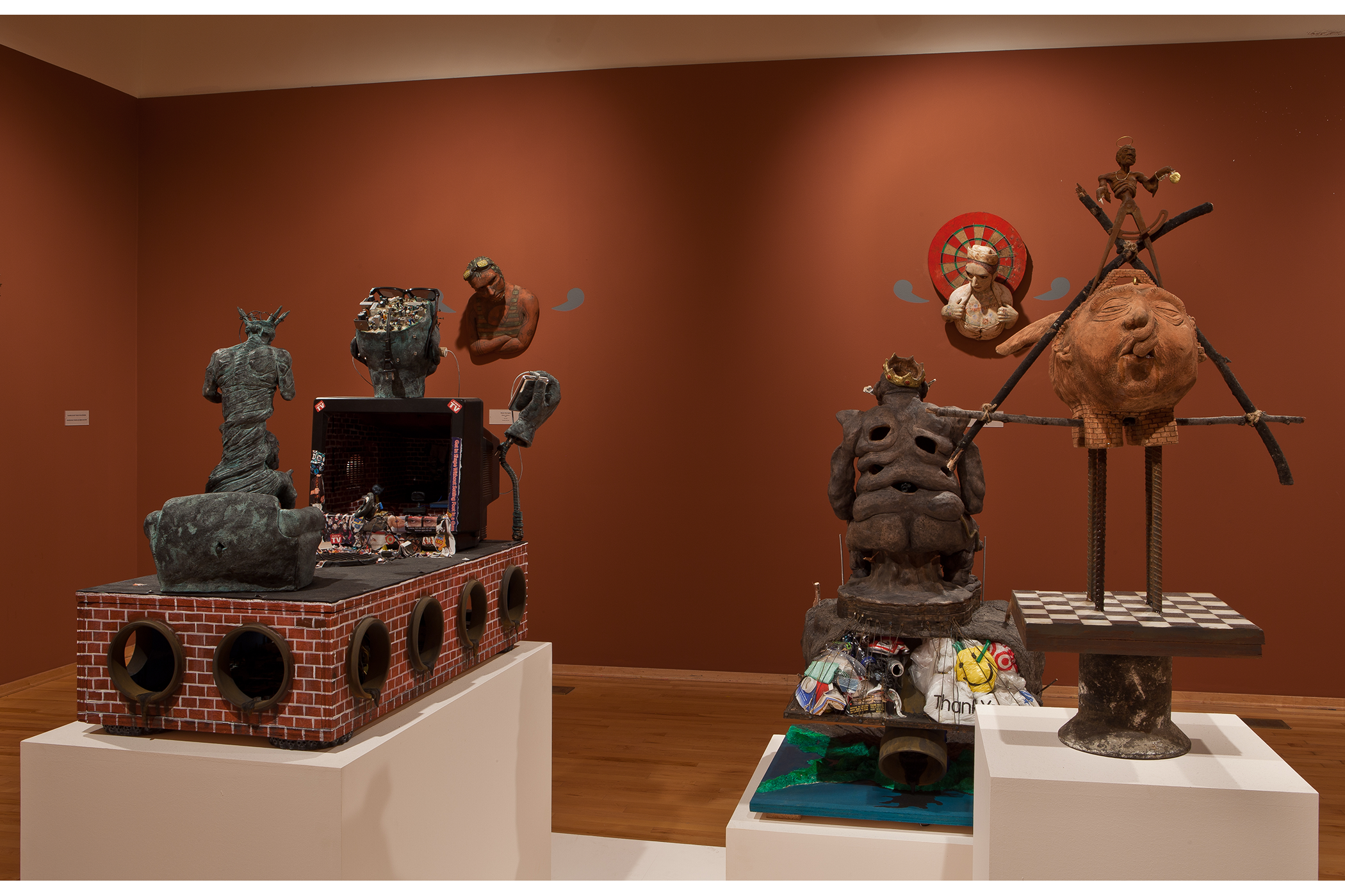 few sculptures displayed in the center of the art gallery.