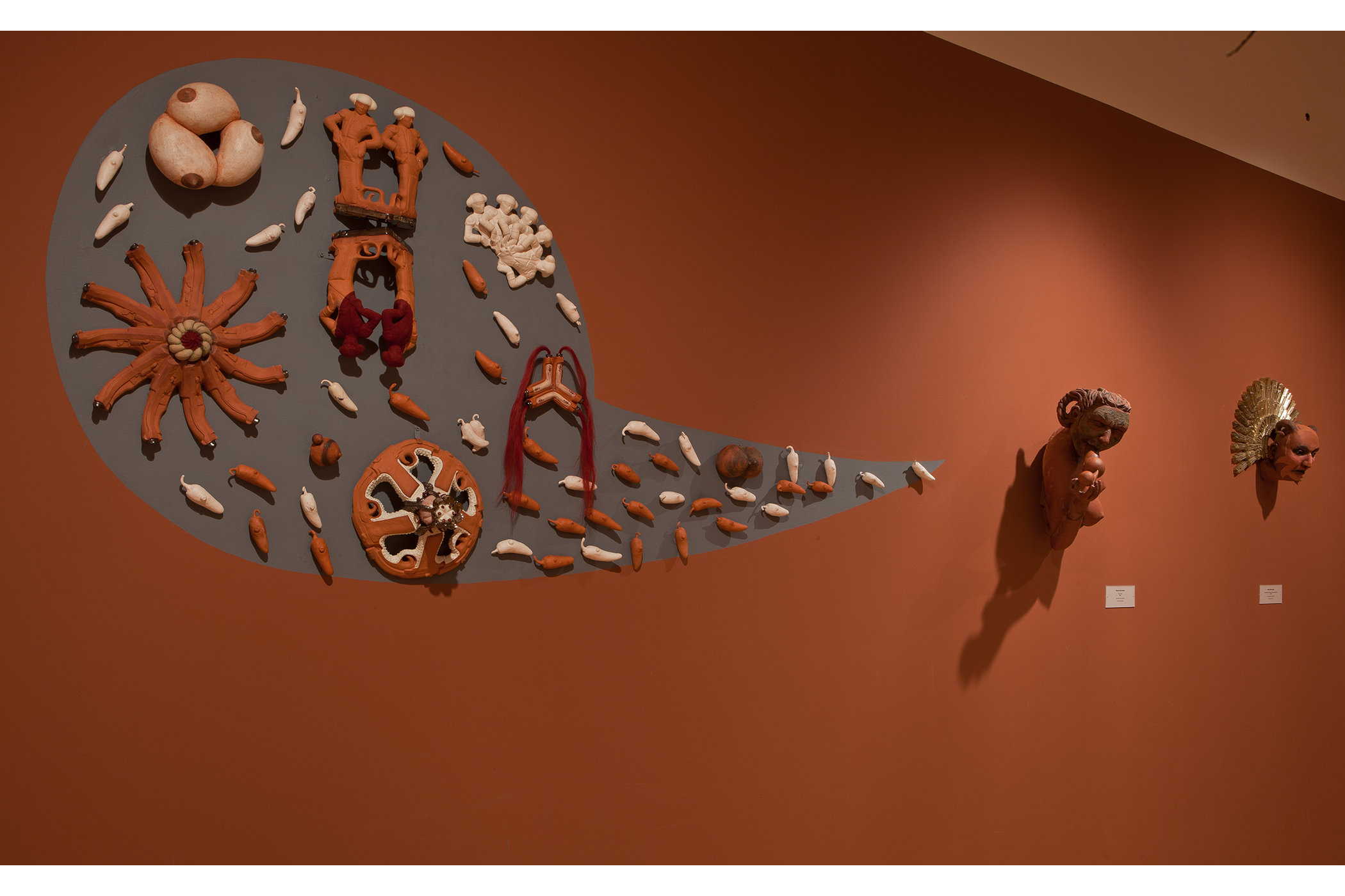 Three head figurines displayed on the gallery wall