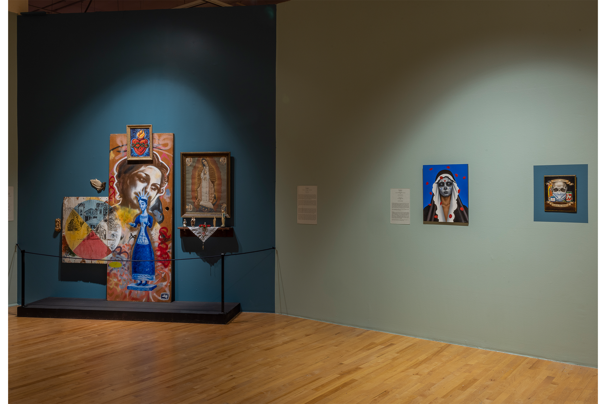 An overview shot of the artwork on display in the teal gallery space.
