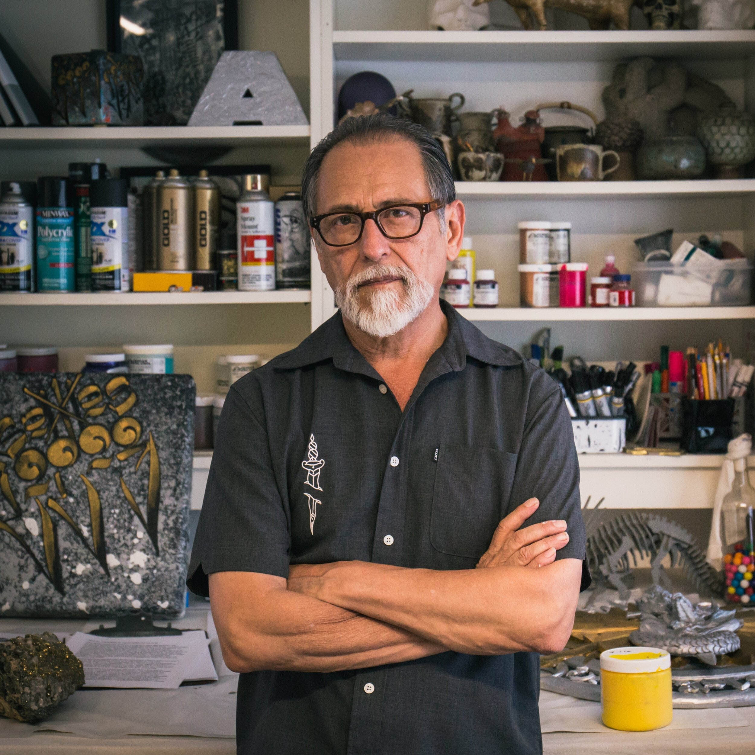 A man with crossed arms poses in front of an art studio
