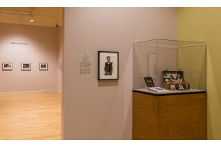 Photo of multiple gallery walls and glass case with artwork