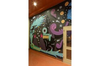 A black and colorful mural on the walls of the museum gallery