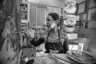Black and white photograph of Rocío Caballero painting in studio