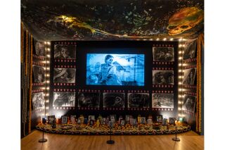 A detail shot of an Ofrenda depicting artwork, image projections, and drawings reminiscent of old movie theater aesthetics.