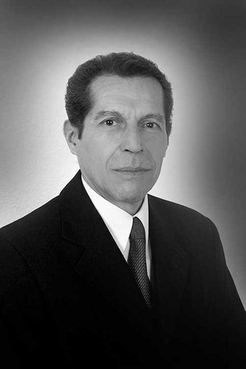 A man in a suit poses for a photo in black and white
