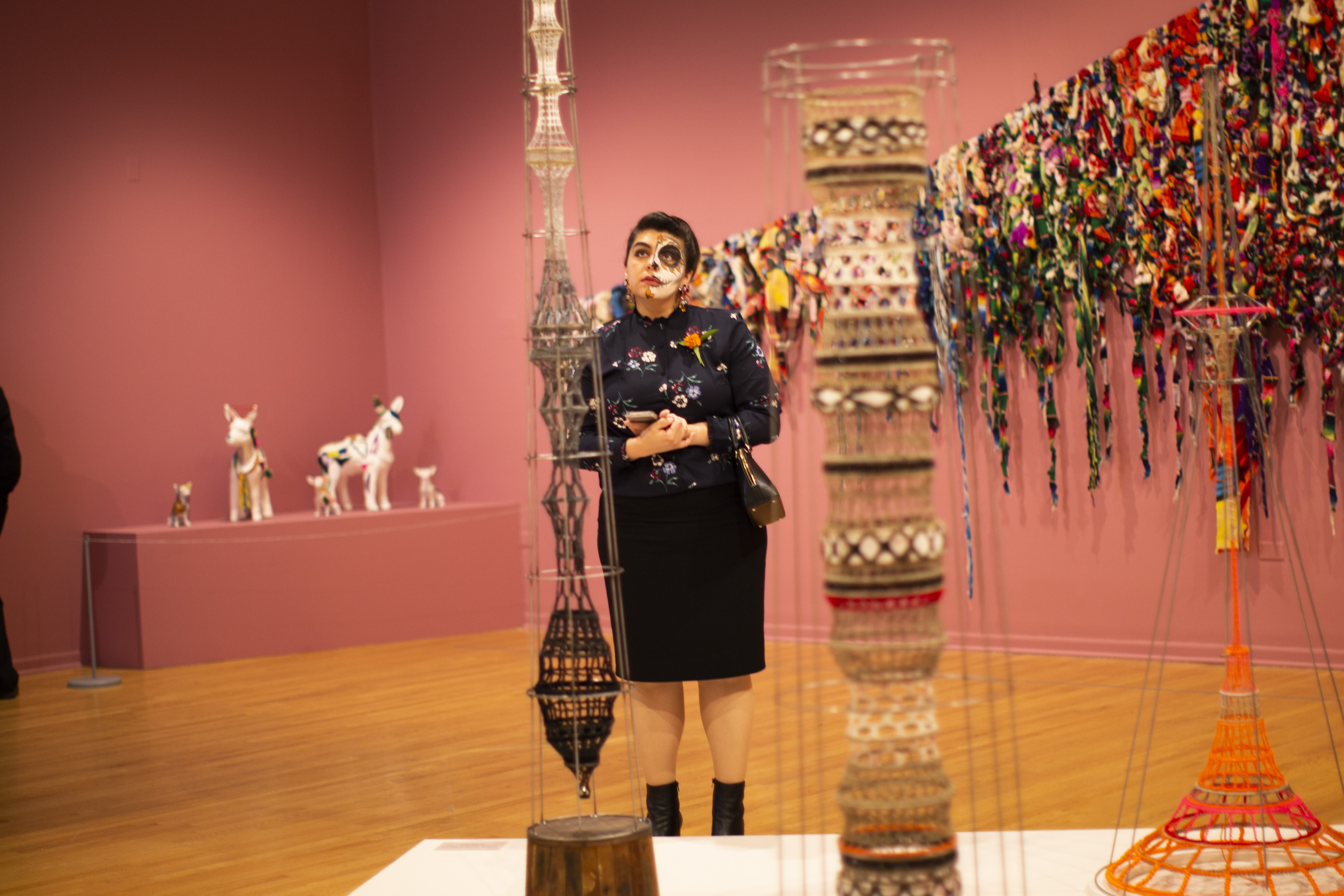 Woman attending Day of the Dead Ball standing in a gallery.
