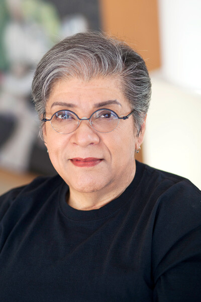 A woman with grey hair and round glasses poses for a photo