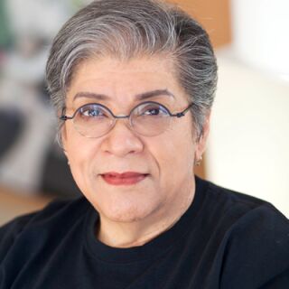 A woman with grey hair and round glasses poses for a photo