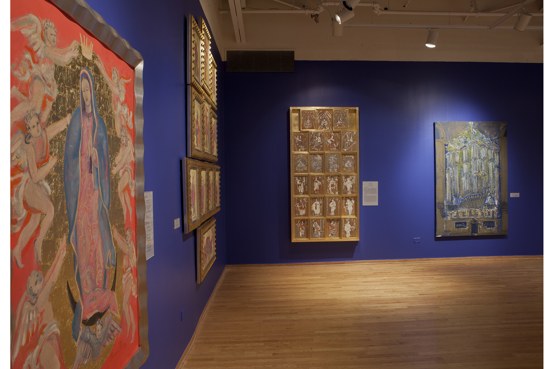 four art pieces hang on the dark blue gallery walls.