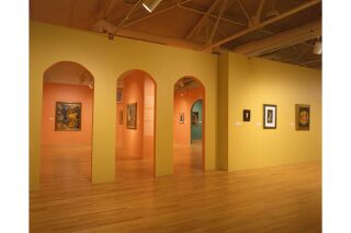 Image of gallery. Yellow and orange walls visible with pieces of Remedios Varo's artwork hanging