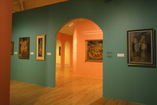 Image of gallery. Teal and orange walls visible with Remedios Varo's artwork hanging