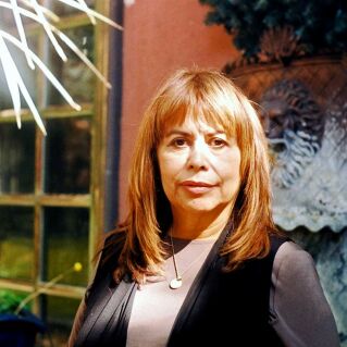 A woman stands in a patio in front of a fountain for a photo