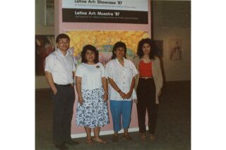 Color photograph of a man and three women standing in front of exhibit sign