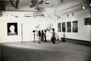 Black and white photograph of four children and adult looking at art in gallery