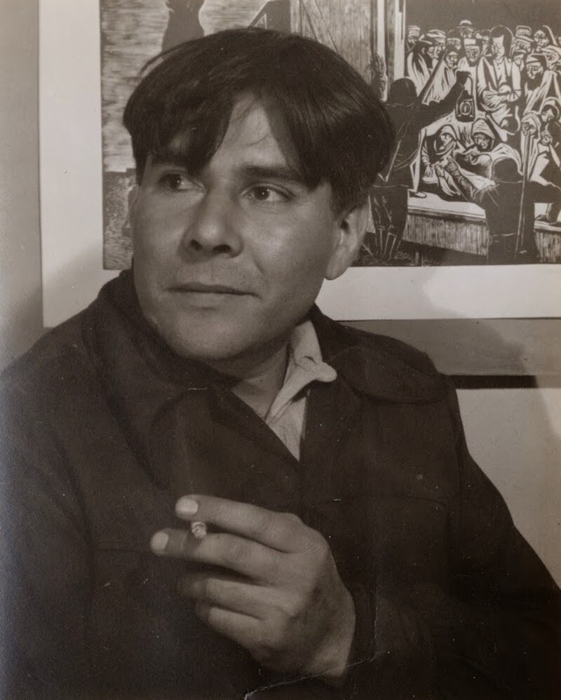 A seated man with a cigarette in hand turns his head