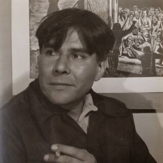 A seated man with a cigarette in hand turns his head