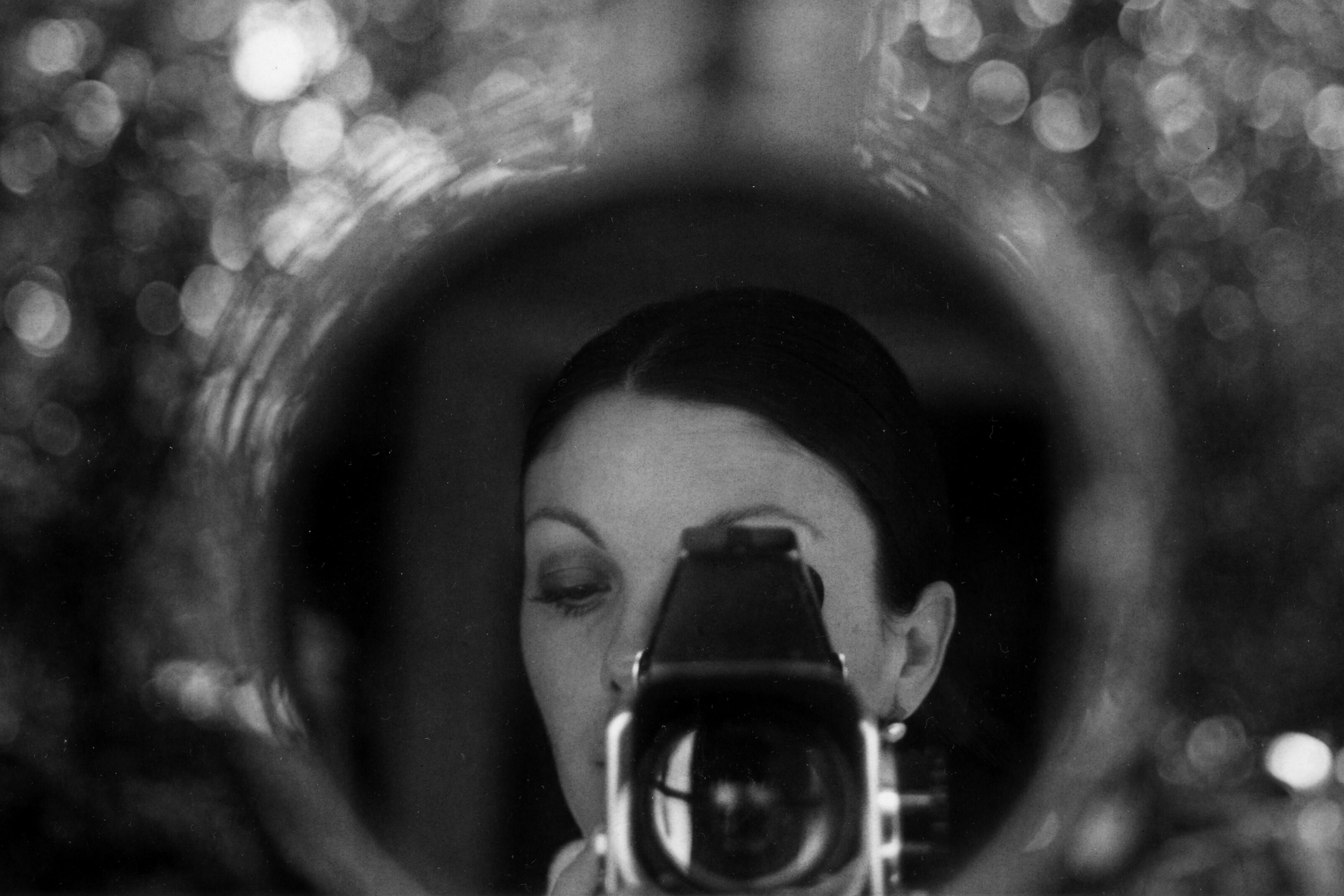 A woman with a large brimmed hat takes a photo of her self in a reflection