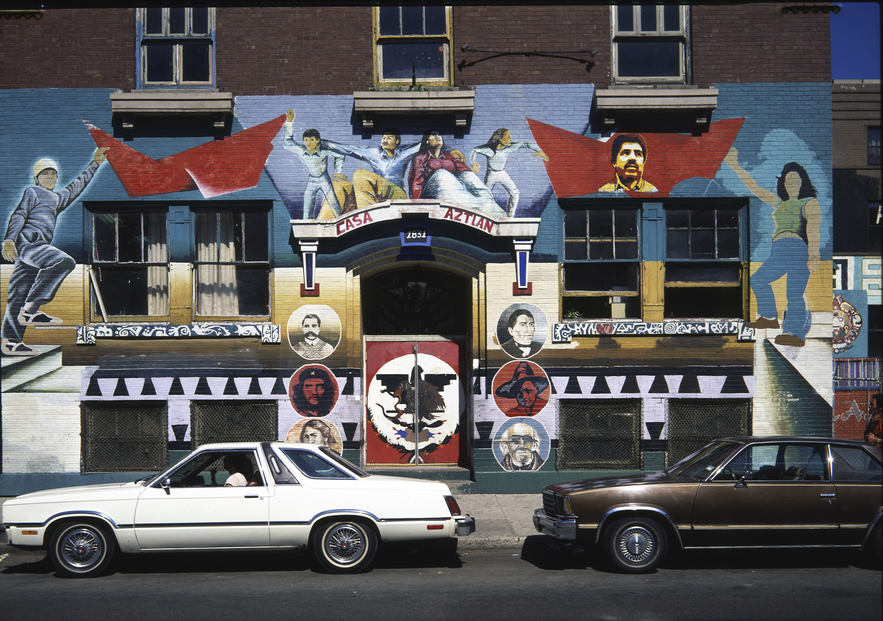 mural in front of building with two cars