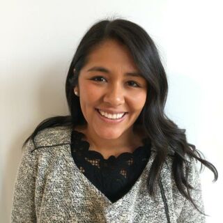 The photograph shows a young woman with long dark hair, a black blouse and a gray jacket, named Alejandra Lara