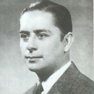 A man in a suit poses for a photo in black and white
