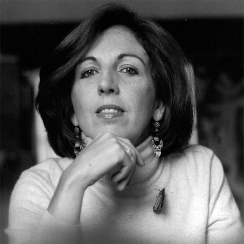 A woman tilts her head upward with her hand on her chin while she poses for a photo