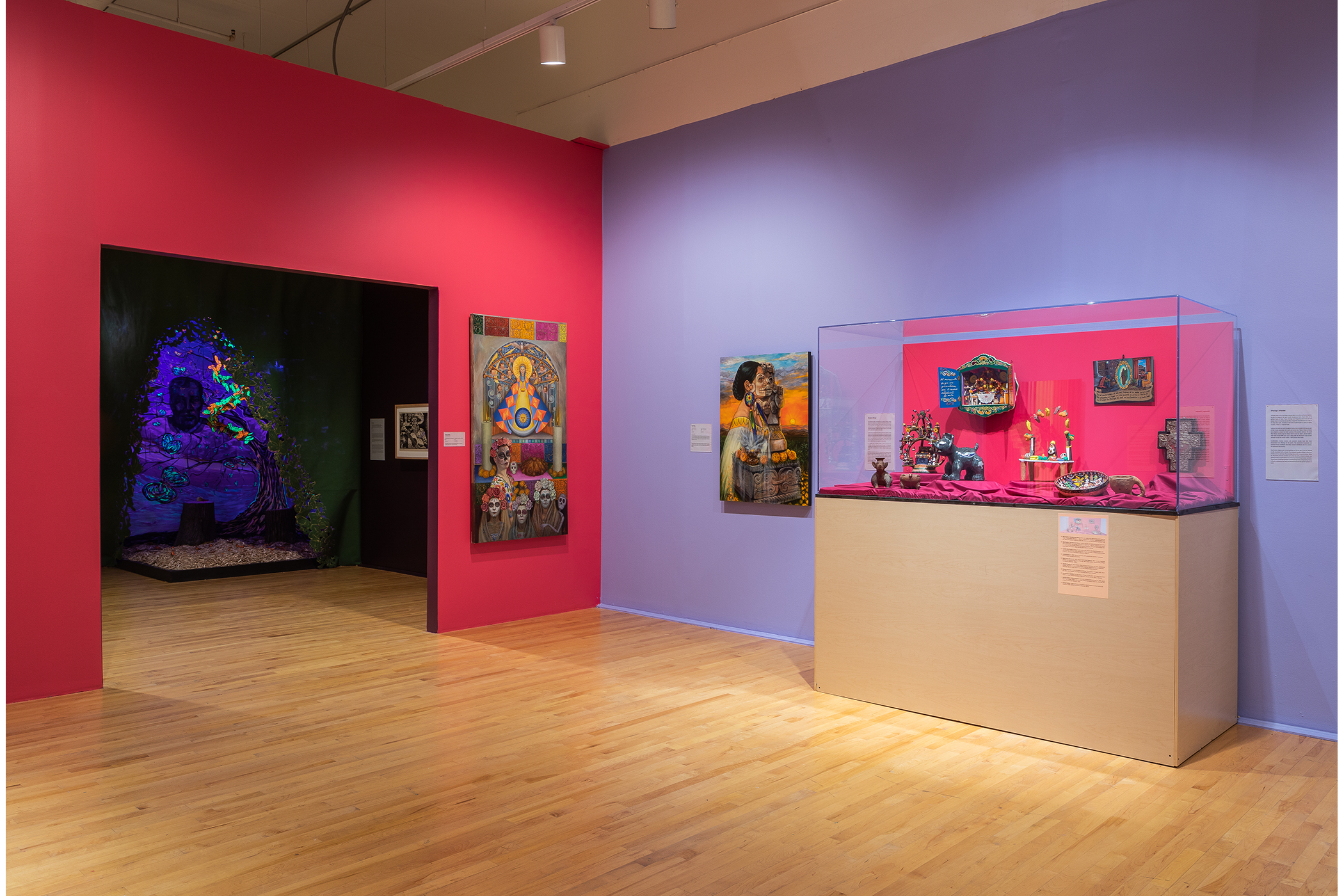 Two paintings are left of a vitrine with various polychrome ceramic objects.