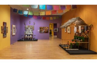 A view of a gallery decorated with papel picado and showcasing art installations