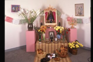 Ofrenda including hanging art, flowers, and a statue of the Virgen