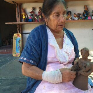 Photo of a Jofefina Aguilar holding a clay sculpture