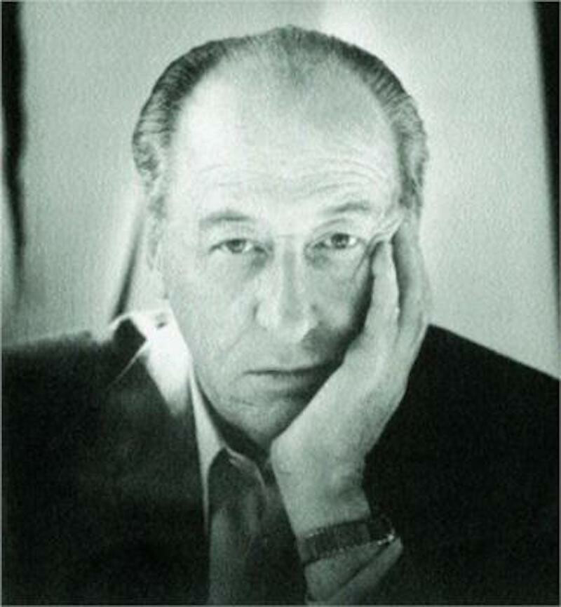 A man with holds his palm to his face and looks directly into the viewer