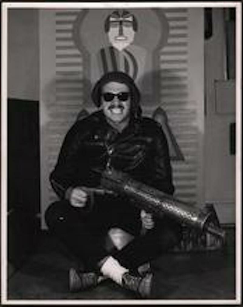 a man wearing dark glasses poses in a chair for a photo