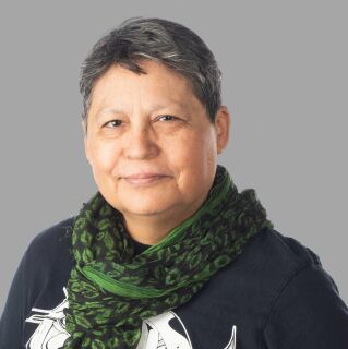 A person with short hair and a green scarf poses for a photo