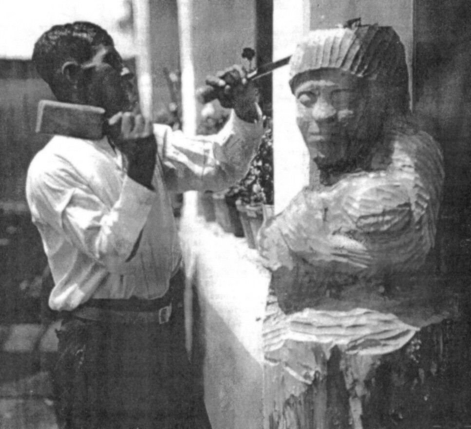 A man uses a chisel to carve a wooden sculpture