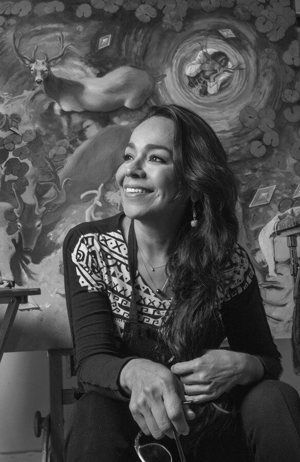 A smiling woman with long hair turns her head as she is photographed
