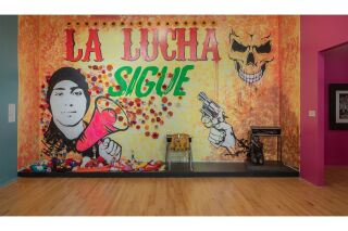 A mural depicting Joaquín “Guac” Oliver with a megaphone surrounded by flowers. Foreground: a statue of a kid hiding underneath a classroom desk.