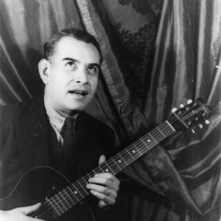 A man holding a guitar poses a photo