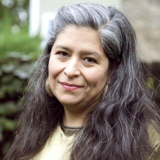 A woman with long black hair poses for a photo