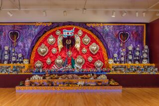 A large mixed media installation with hearts and photographs on a gallery wall