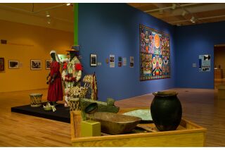 Photo of multiple gallery walls, with focus on 3-dimensional artifacts in center of room