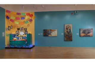 An altar decorated with photos, papeles picados, butterflies, and blue lights; dynamic paintings depicting: a stone warrior, a stone lady with a halo, and a stone skeleton.