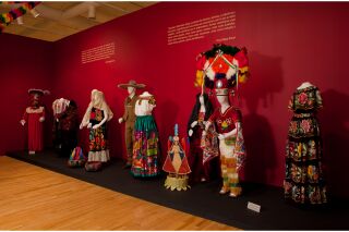 Two Fray Diego Duran quotes on the gallery wall with regional traditional attire displayed underneath