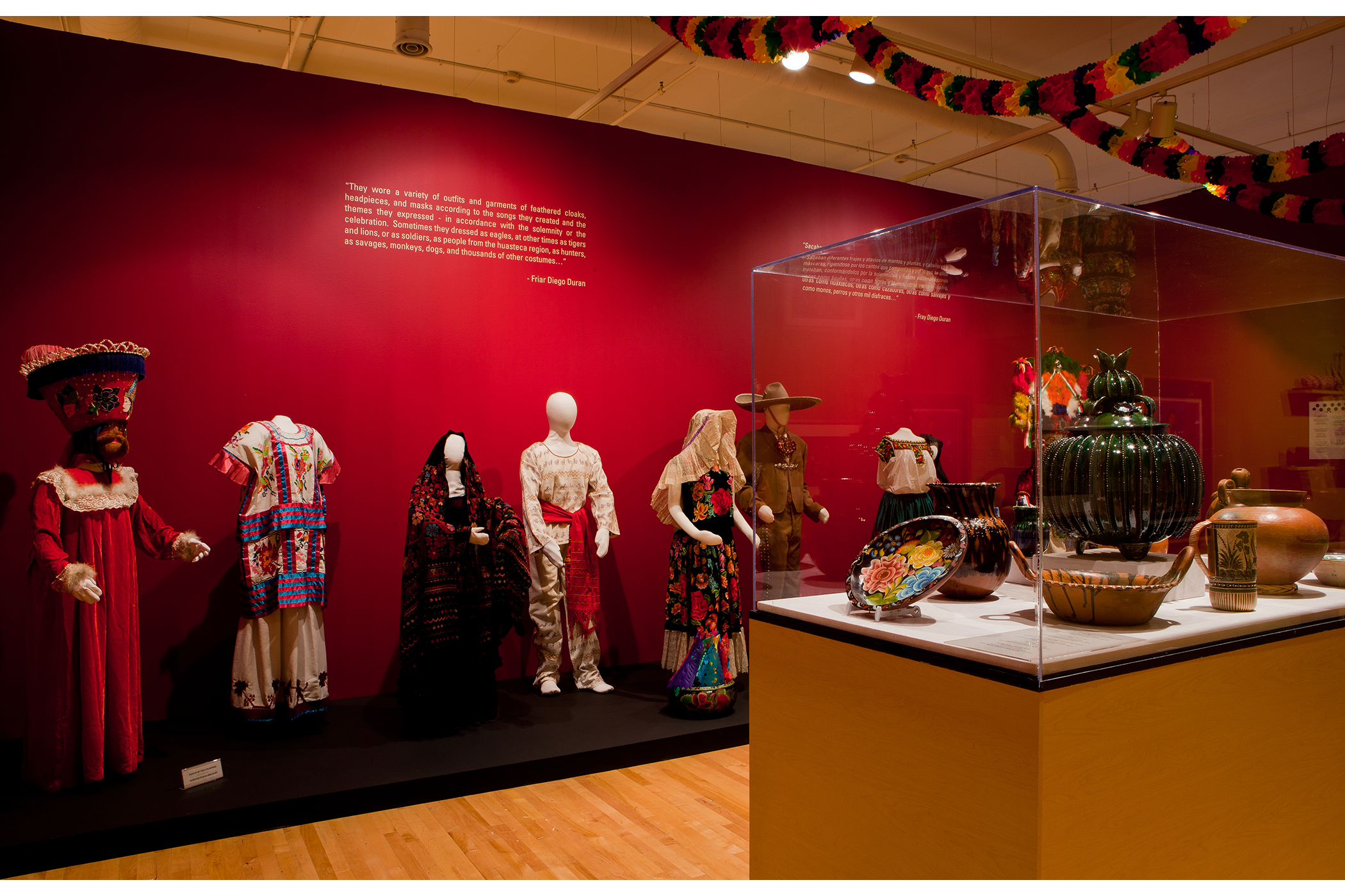 collection of regional traditional attire, and a floral plate and monotone pots displayed on a podium in the gallery
