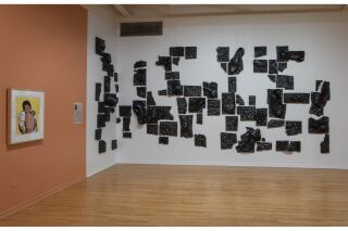 A closer view of Mourning Portrayal: A collection of black broken glazed ceramic pieces laid across the wall; shoes and other debris imprinted across them.