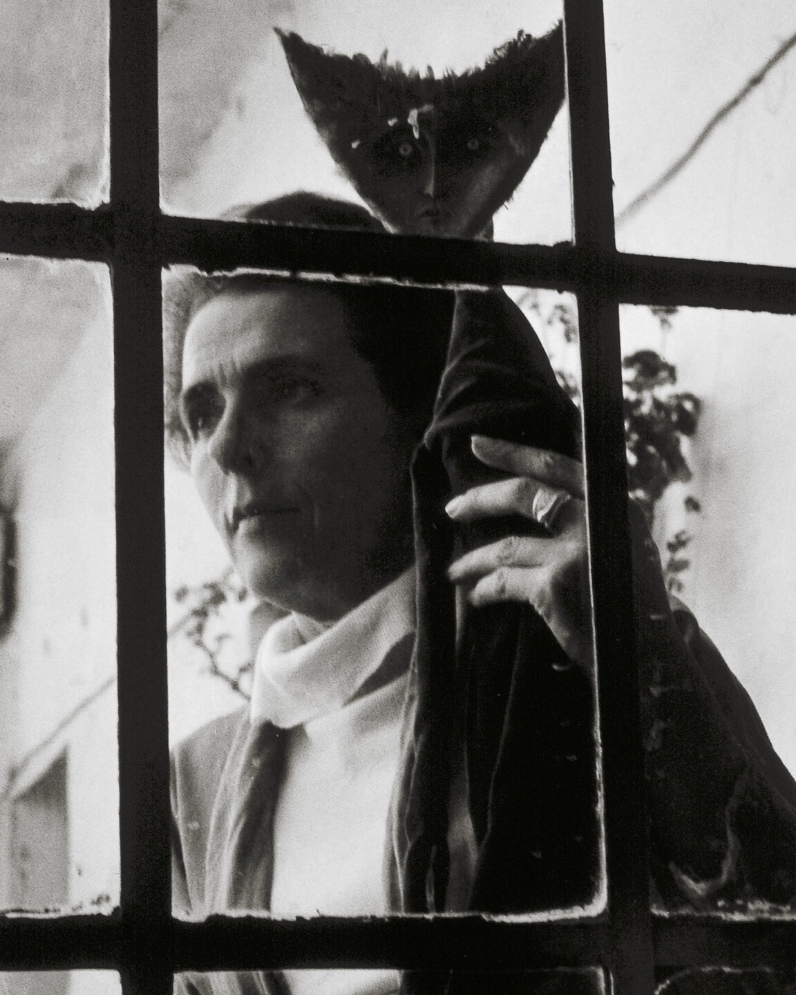 View through a gate of a woman holding an upside down fish sculpture