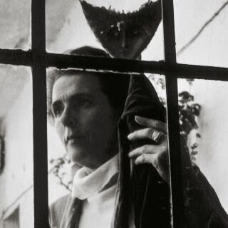 View through a gate of a woman holding an upside down fish sculpture