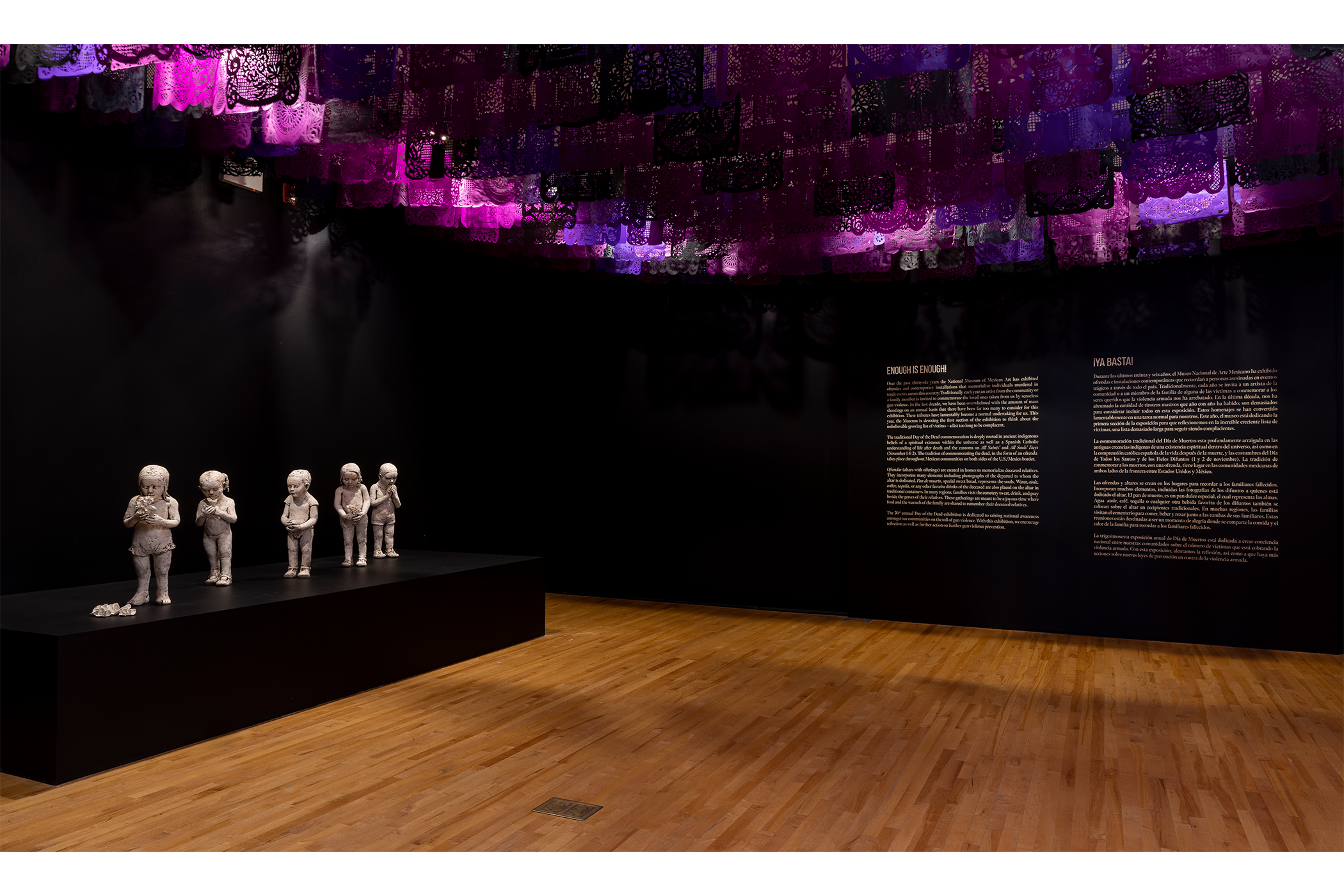 A black room with magenta, purple, and black papeles picados hanging across the ceiling.