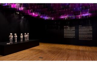 A black room with magenta, purple, and black papeles picados hanging across the ceiling.