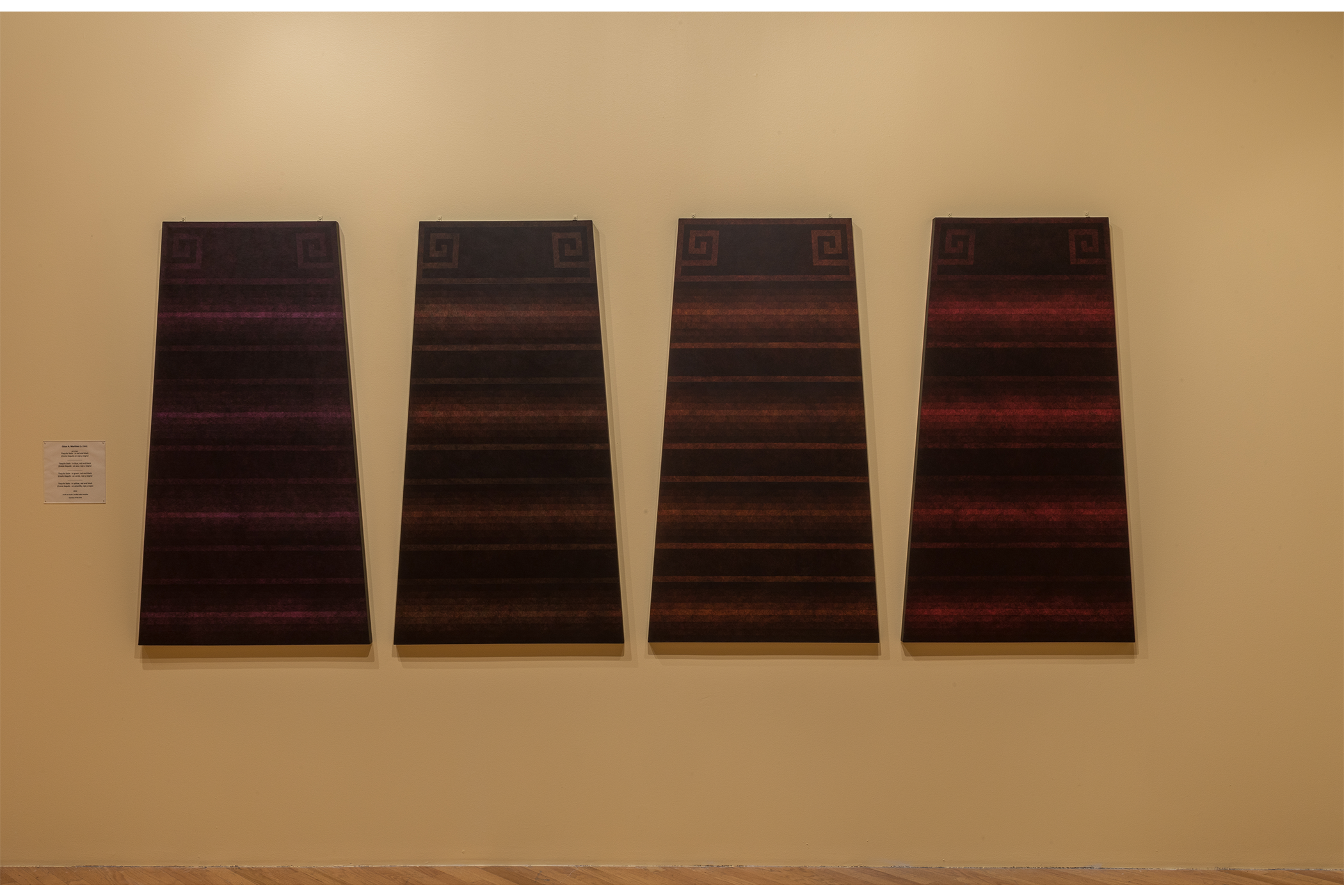 An upclose shot of the 4 Tlaquilo Steles on display. Each one, a different color combination.  Conbinations from left to right: blue red and black. green red and black. yellow red and black. red and black.