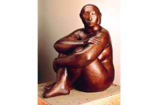 Sculpture of woman in seated position, with legs pulled up to the chest