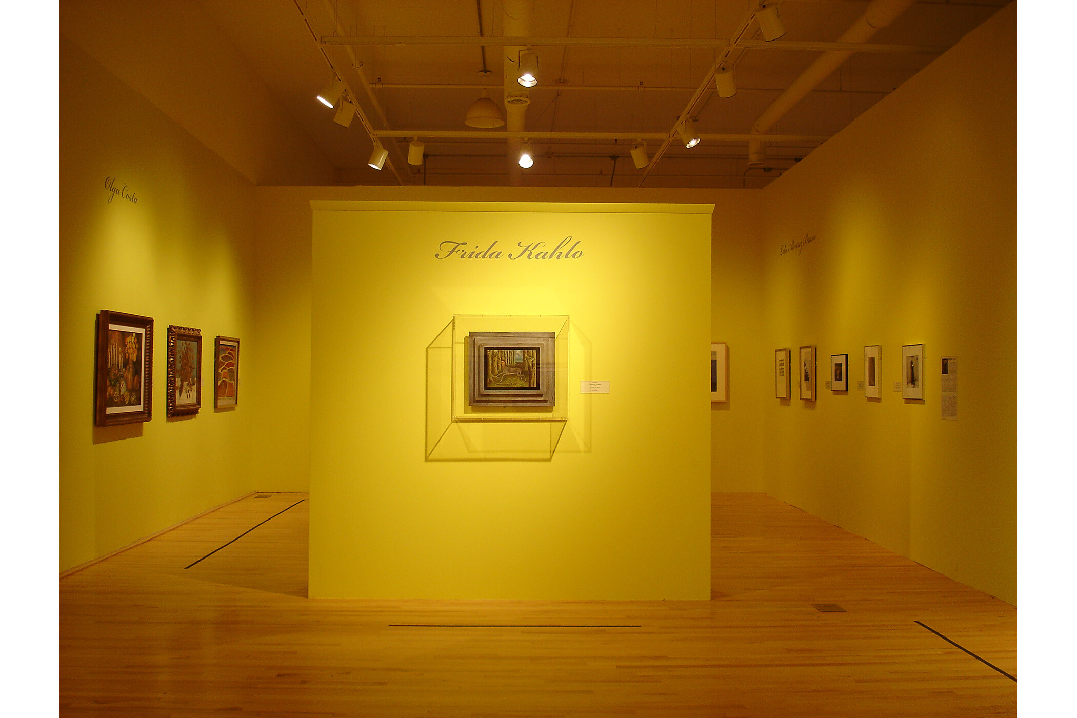 Gallery view shows three walls but focuses on central wall with one painting depicting the body of a deer with a woman’s head.